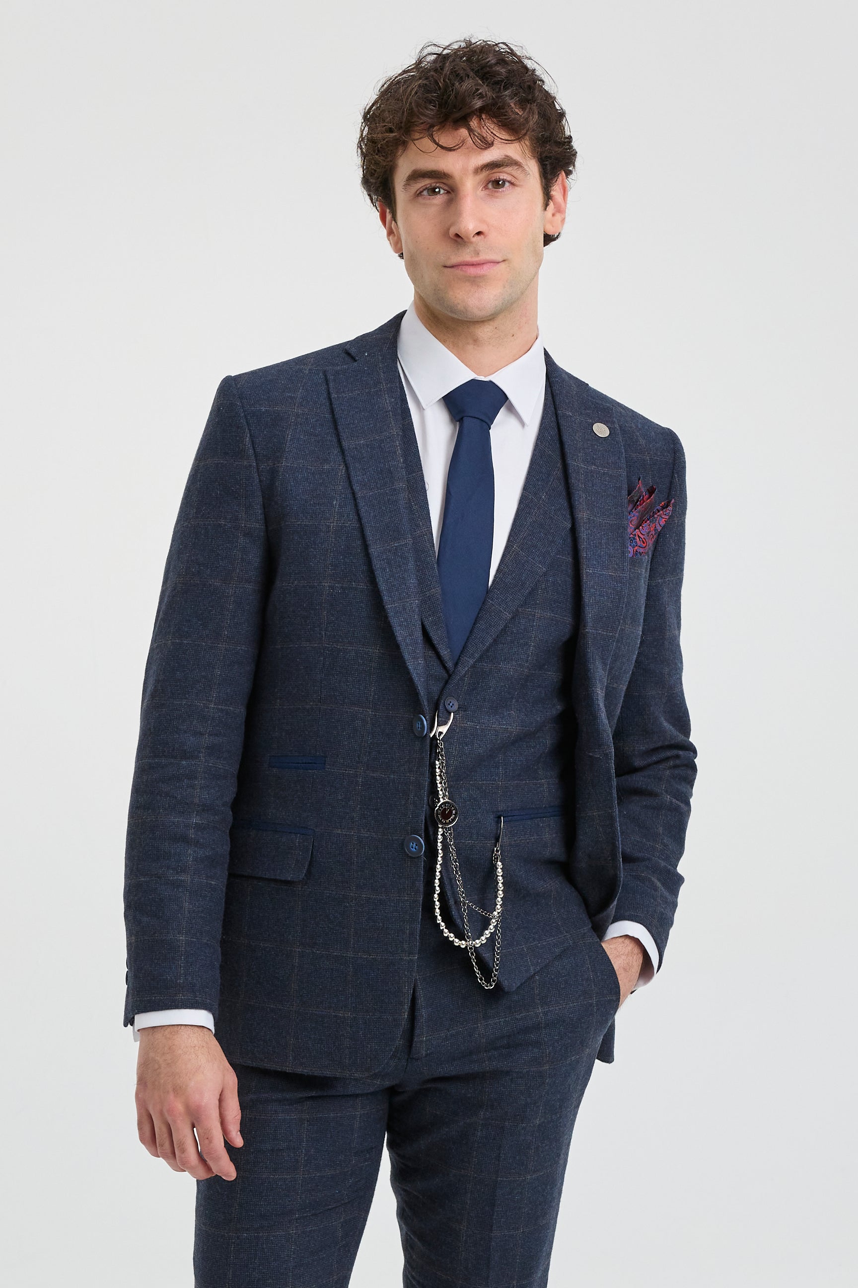 Man wearing a blue checkered suit with a white shirt and blue tie on a light gray background