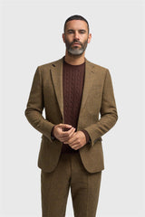 Man wearing a brown suit and maroon sweater on a white background